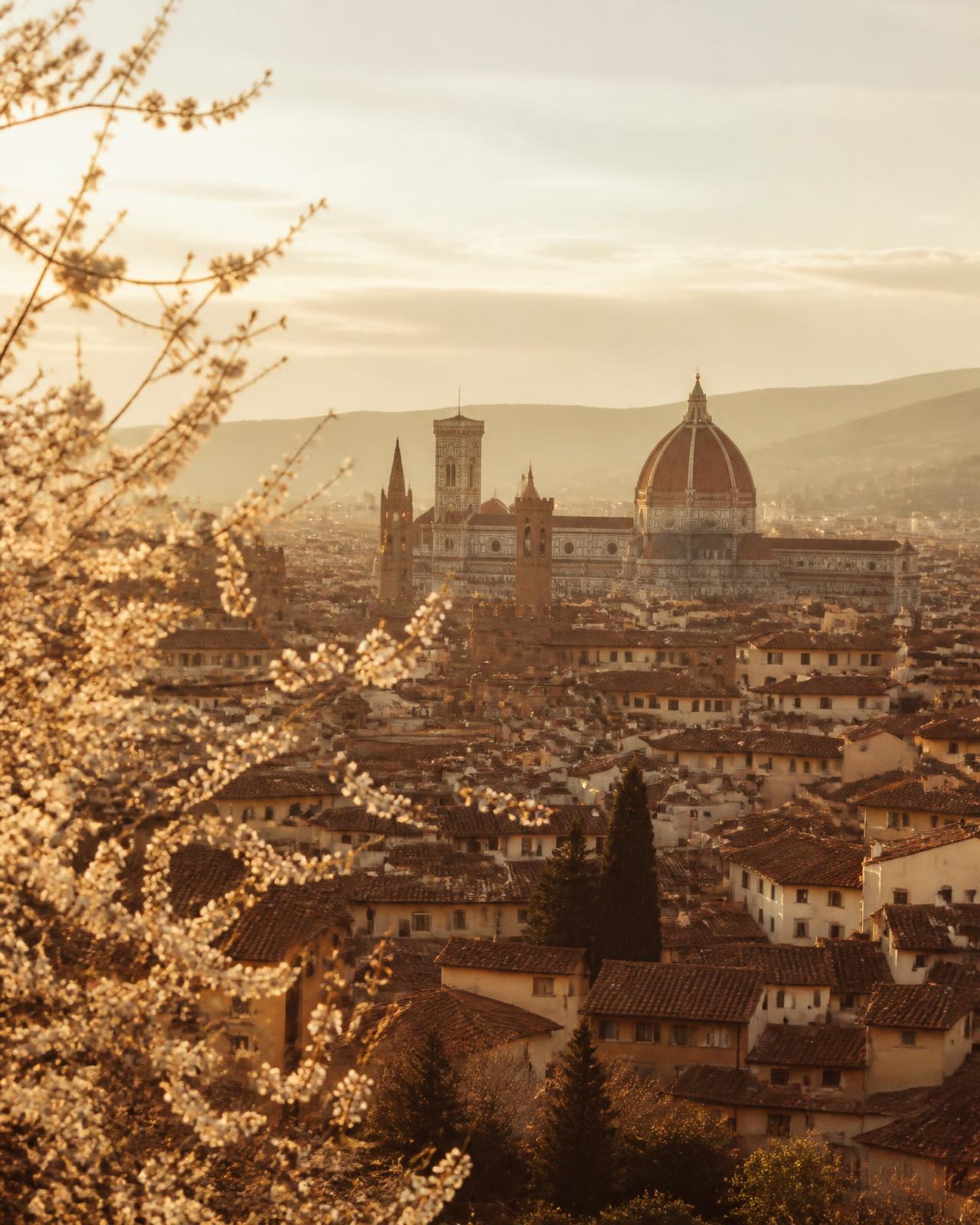 Vista de uma cidade italiana histórica ao entardecer, com cúpula e telhados de terracota